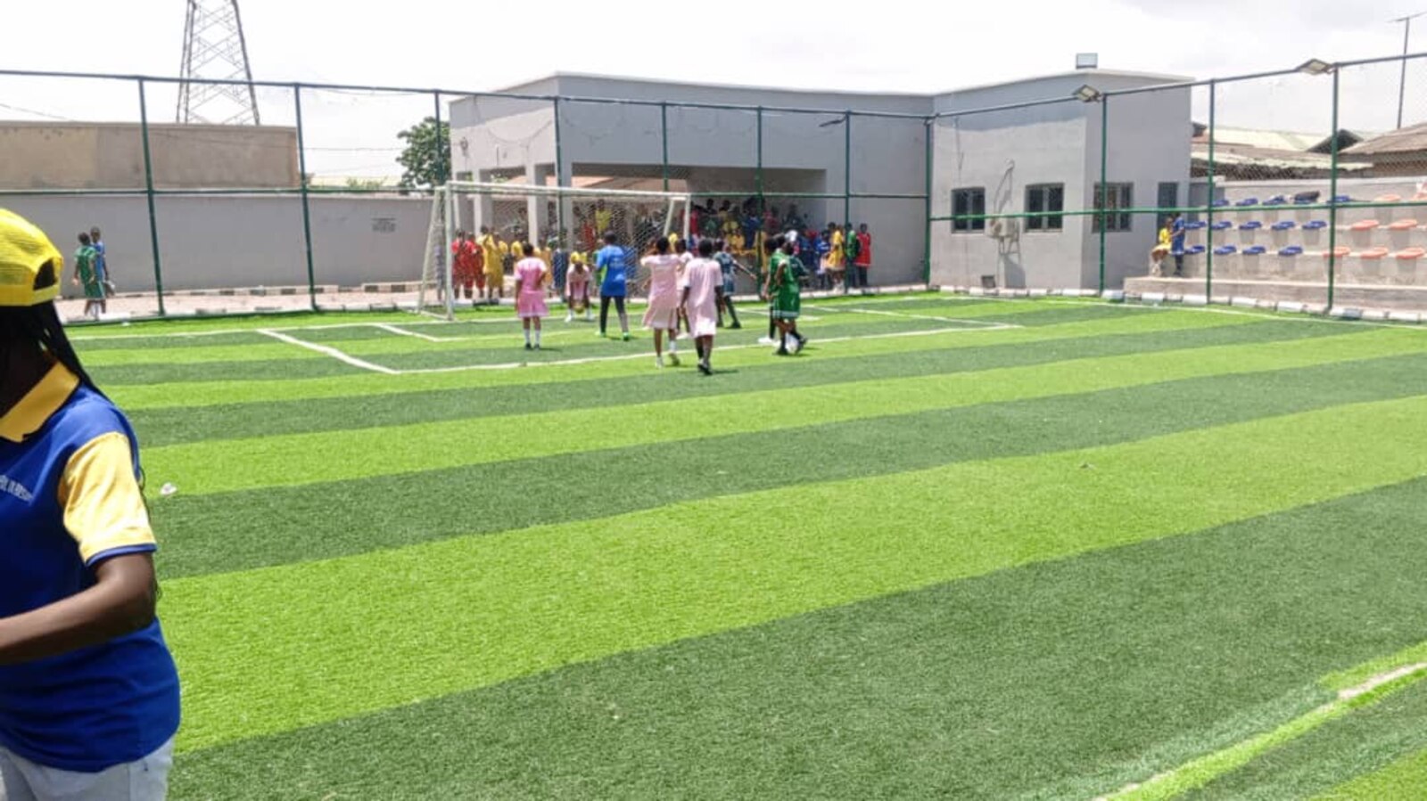 Adetola Comprehensive College students playing on the astroturf pitch in front of the school building