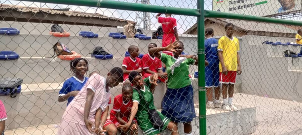 Adetola pupils in house colours cheering by the pitch