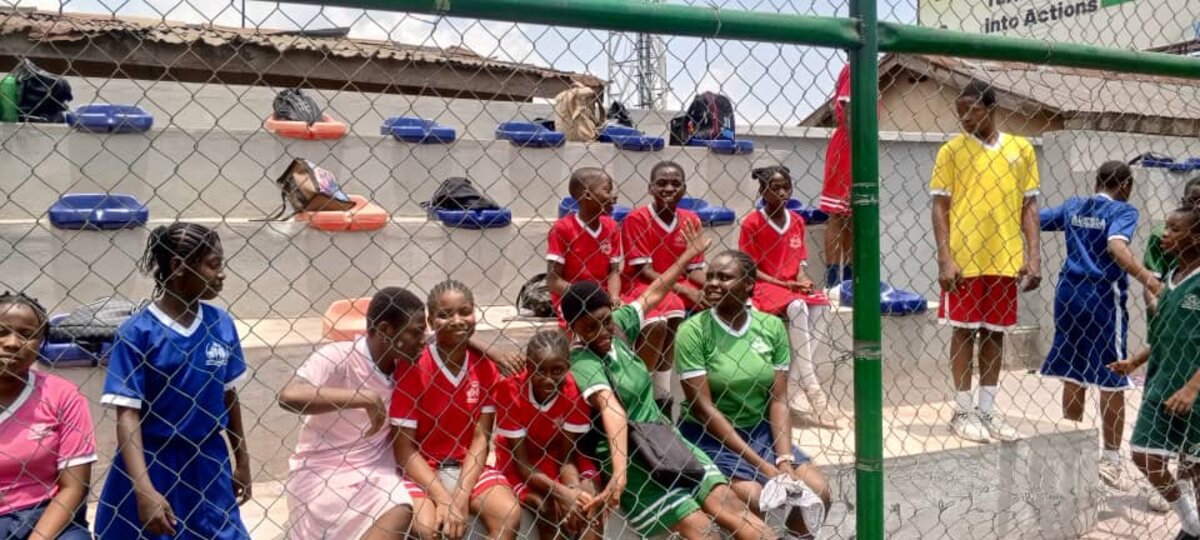 Adetola students sitting together on the school's astroturf football pitch